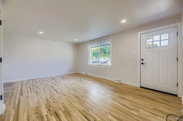an empty room with wooden floor and windows