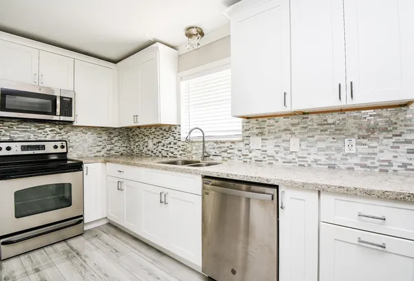 a kitchen with granite countertop white cabinets sink and stainless steel appliances
