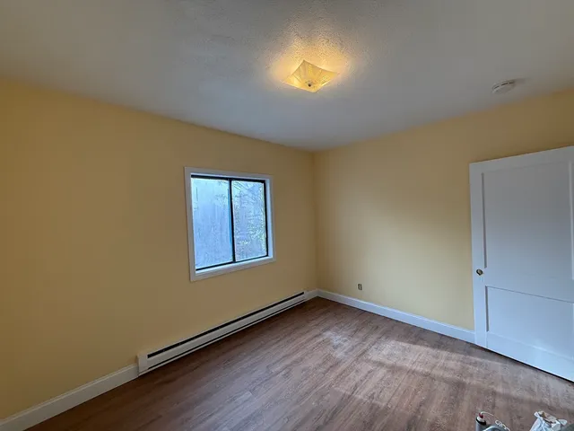 an empty room with a window and wooden floor