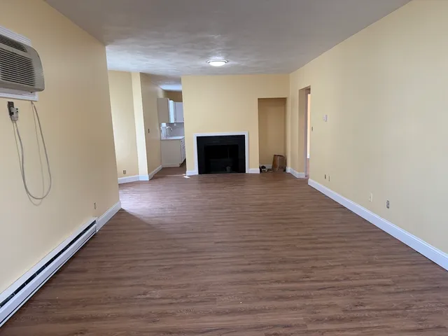 a view of empty room with wooden floor and fireplace