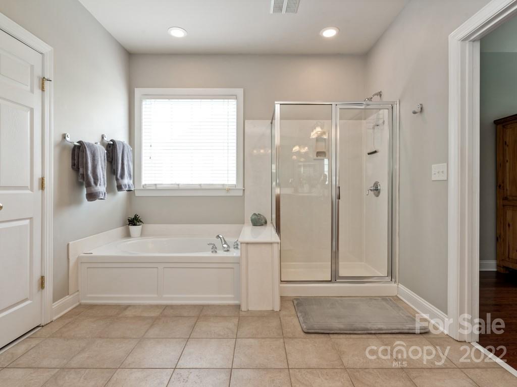 8603 Dansington Court Waxhaw, NC 28173 - Photo 26 of 45 a bathroom with a tub sink a mirror and a shower