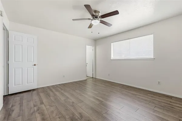 an empty room with wooden floor closet and windows