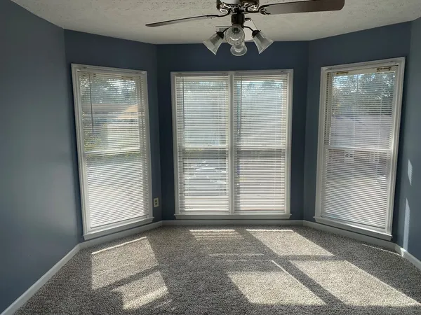 a view of a livingroom with a chandelier fan and windows