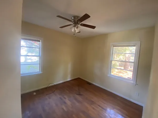 a view of an empty room with wooden floor and a window