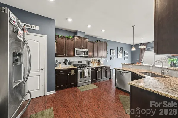 a kitchen with stainless steel appliances granite countertop a refrigerator a sink a stove and oven