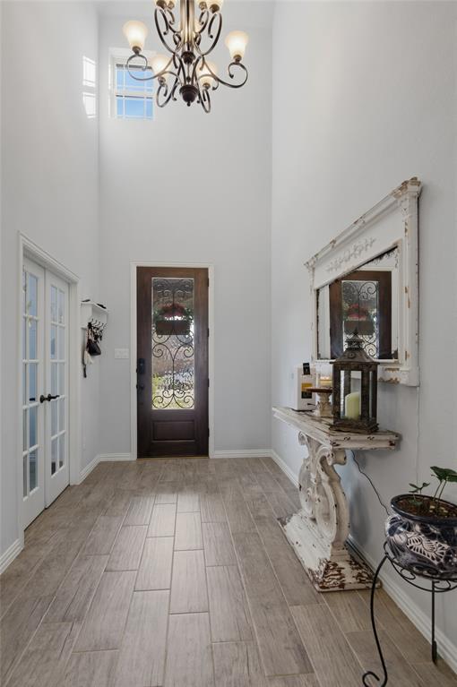 464 LeTara Ranch Drive Haslet, TX 76052 - Photo 6 of 37 Two-story foyer featuring a decorative chandelier, a transom window, a dark wood-finish front door with an ornate glass insert, wood-finish tile flooring, and white trim throughout