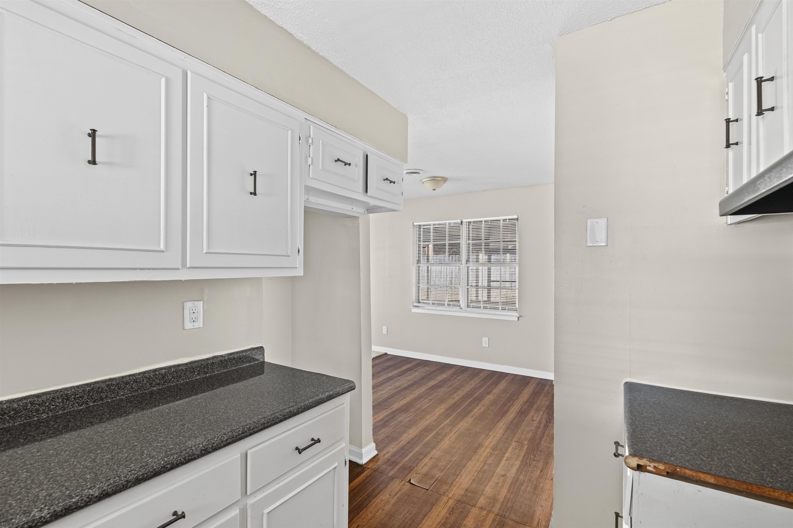 4982 Holly Ridge Drive Memphis, TN 38118 - Photo 19 of 26 a kitchen with granite countertop white cabinets and a wooden floor