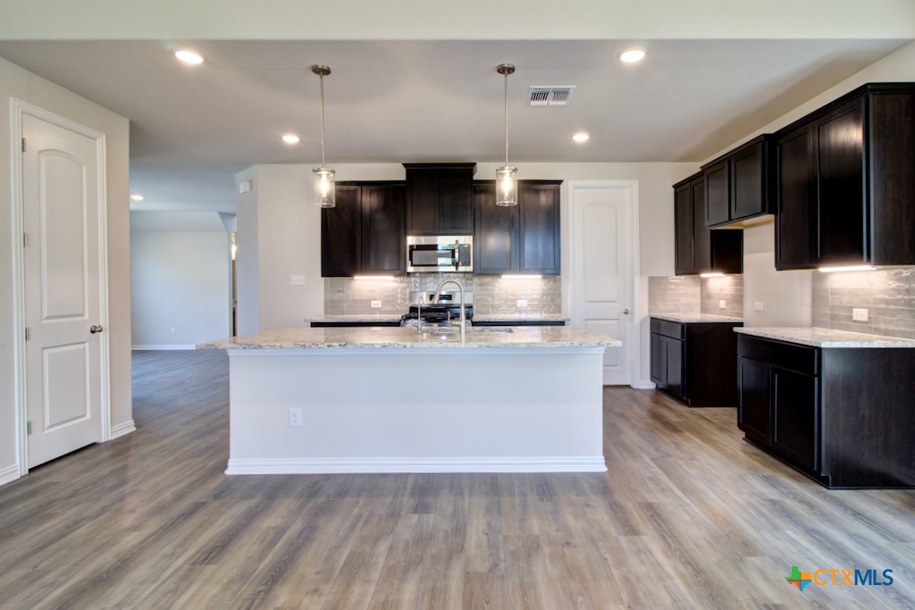 2129 Shepards Street Seguin, TX 78155 - Photo 8 of 29 a large kitchen with stainless steel appliances kitchen island granite countertop a stove and a wooden floors