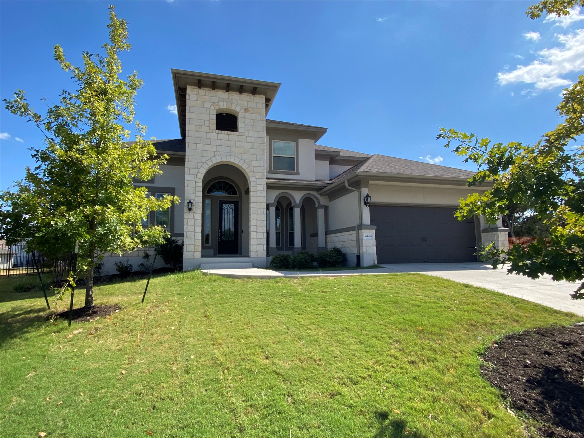 Mediterranean / spanish house featuring stone siding, stucco siding, a garage, and a front yard