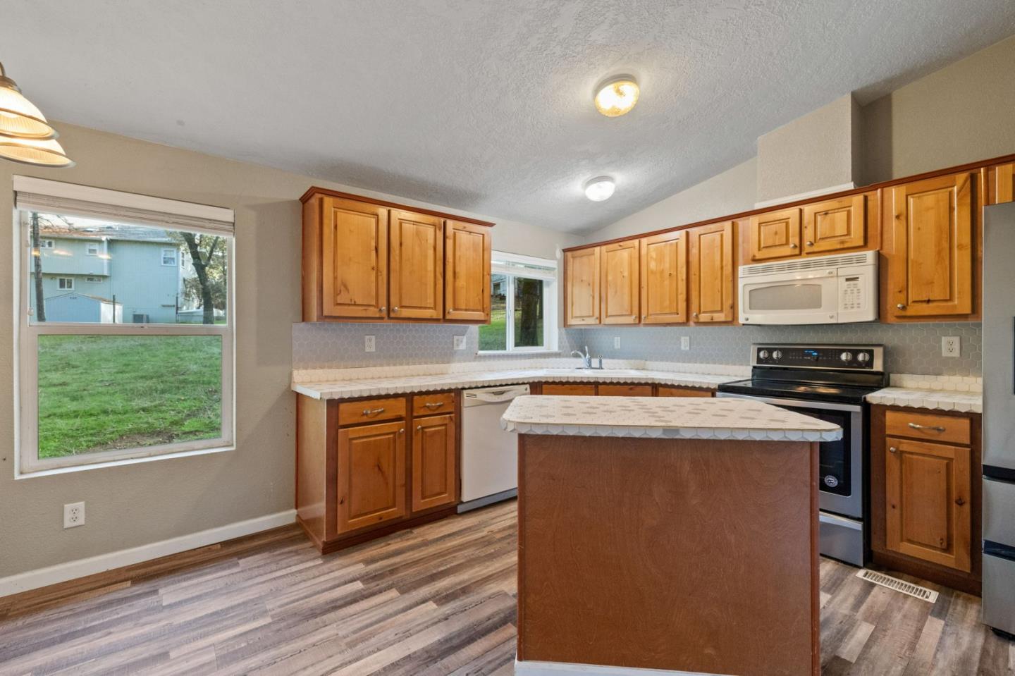 19307 Ferretti Road Groveland, CA 95321 - Photo 7 of 33 a kitchen with stainless steel appliances granite countertop wooden cabinets a stove top oven a sink and dishwasher with wooden floor
