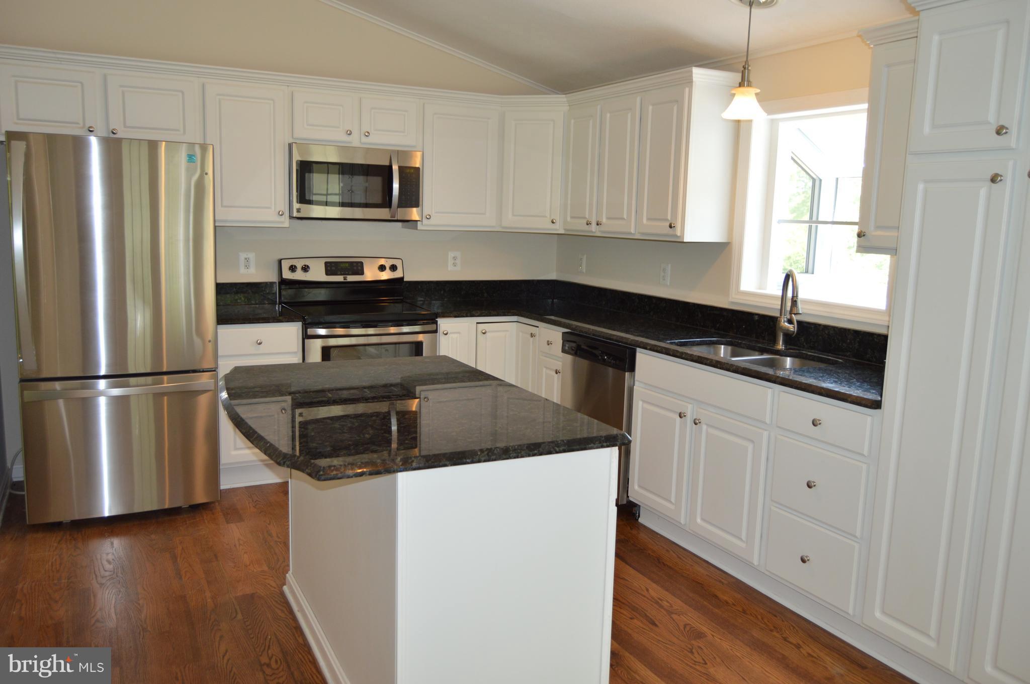 6034 Linden Road St. Leonard, MD 20685 - Photo 2 of 22 a kitchen with a sink a microwave a refrigerator and cabinets