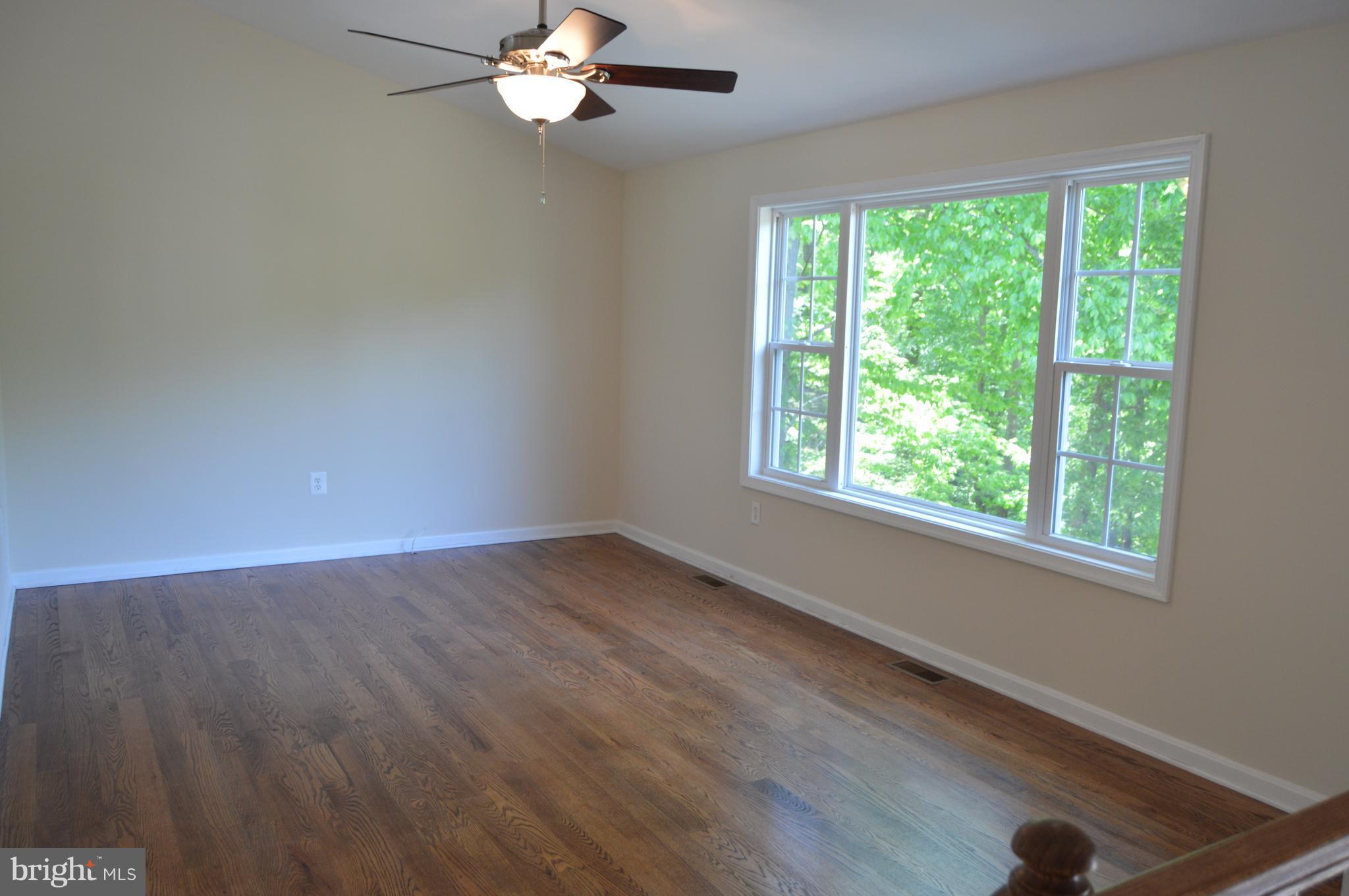 6034 Linden Road St. Leonard, MD 20685 - Photo 5 of 22 a view of an empty room with wooden floor and a window