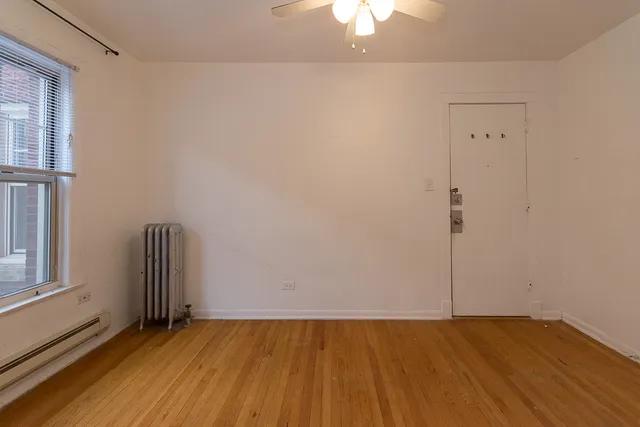 an empty room with a ceiling fan and wooden floor