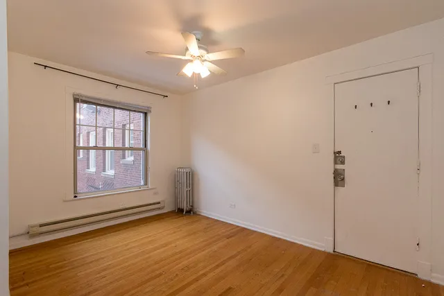 an empty room with wooden floor fan and windows