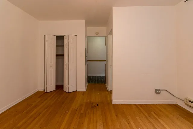 an empty room with wooden floor and entrance