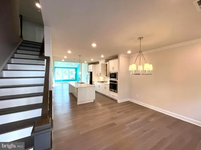 a kitchen with stainless steel appliances granite countertop a refrigerator and a stove top oven with wooden floor