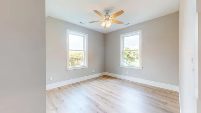 an empty room with wooden floor and windows