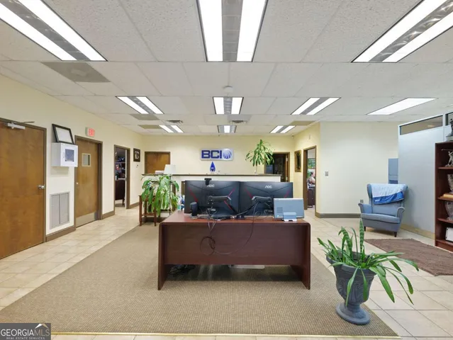 a living room with furniture potted plant and kitchen view