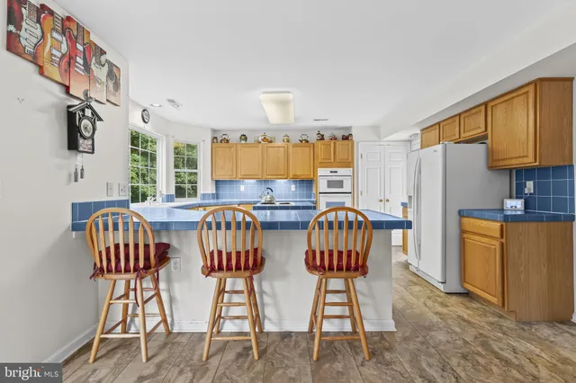 a view of kitchen with granite countertop dining table chairs cabinets and stainless steel appliances