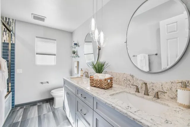 a bathroom with a granite countertop sink a toilet and a mirror