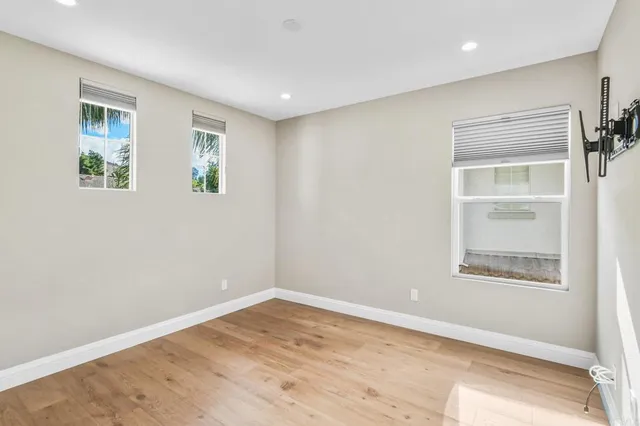 a view of empty room with wooden floor and fan