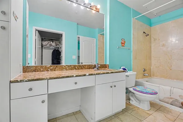 a bathroom with a granite countertop toilet sink and mirror