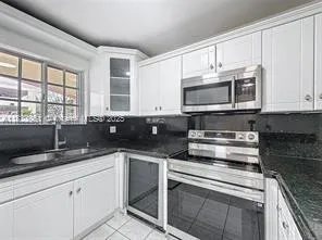a kitchen with granite countertop white cabinets stainless steel appliances and a sink