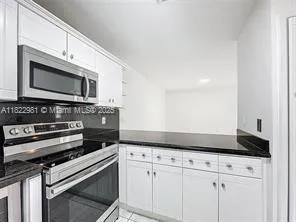 a kitchen with granite countertop a stove microwave and oven with white cabinets
