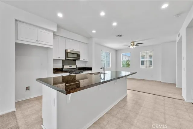 a kitchen with granite countertop a sink and white cabinets