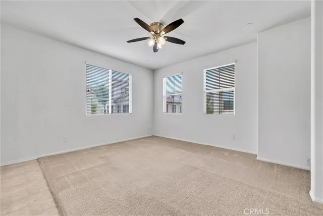an empty room with windows and ceiling fan
