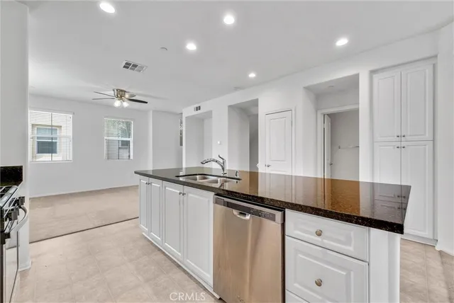 a kitchen with granite countertop a sink and white cabinets