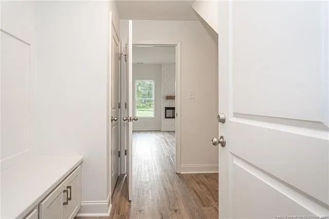 a view of a hallway with wooden floor and a bathroom