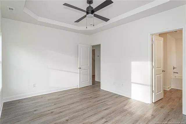 an empty room with wooden floor and a ceiling fan