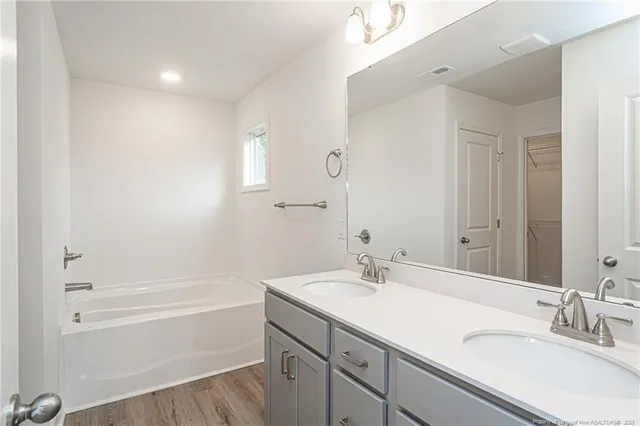 a bathroom with a tub sink double vanity and shower