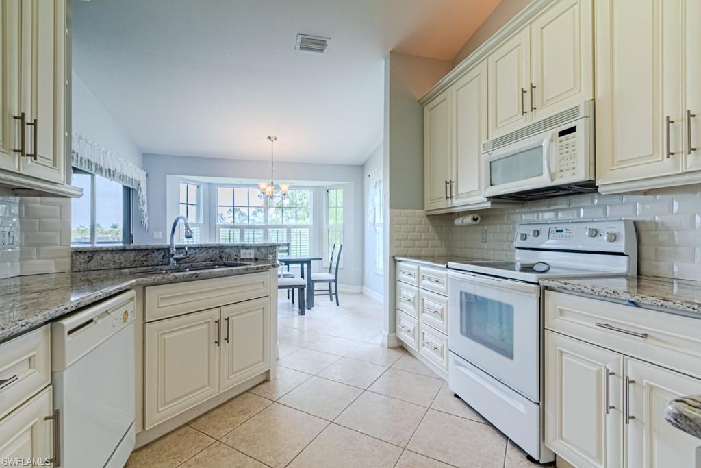 6015 Pinnacle Lane, Unit 5 Naples, FL 34110 - Photo 11 of 25 a kitchen with white cabinets and white appliances