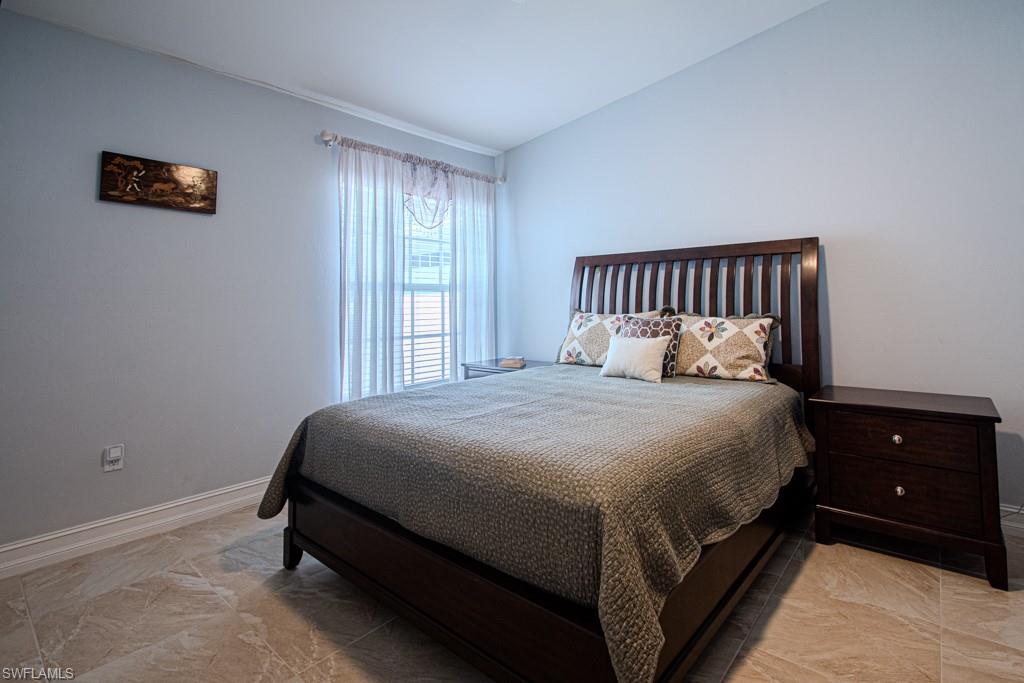 6015 Pinnacle Lane, Unit 5 Naples, FL 34110 - Photo 18 of 25 a large bed sitting in a bedroom next to a window and a chandelier