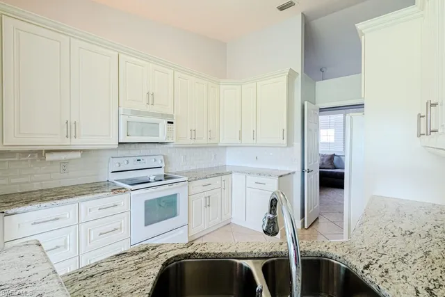 a kitchen with white cabinets and white appliances