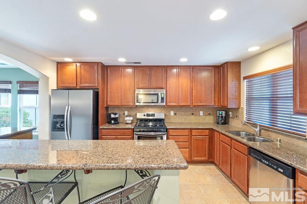 7686 Pebblestone Way Reno, NV 89523 - Photo 13 of 35 a kitchen with stainless steel appliances granite countertop a stove top oven a sink refrigerator and microwave