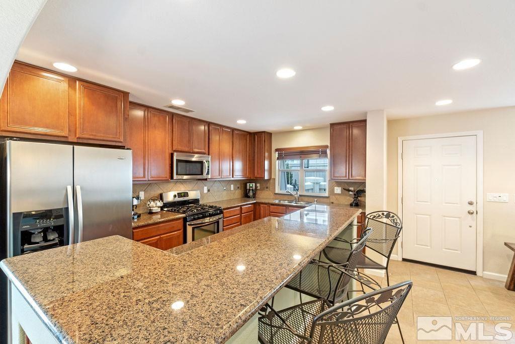 7686 Pebblestone Way Reno, NV 89523 - Photo 14 of 35 a kitchen with stainless steel appliances granite countertop a stove top oven a sink a dining table and chairs