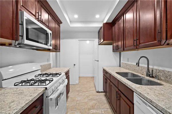 a kitchen with stainless steel appliances granite countertop a sink a stove a oven with wooden cabinets