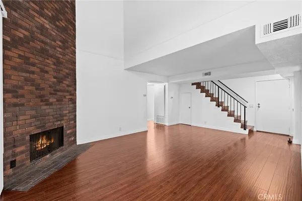 a view of an empty room with wooden floor fireplace and a window