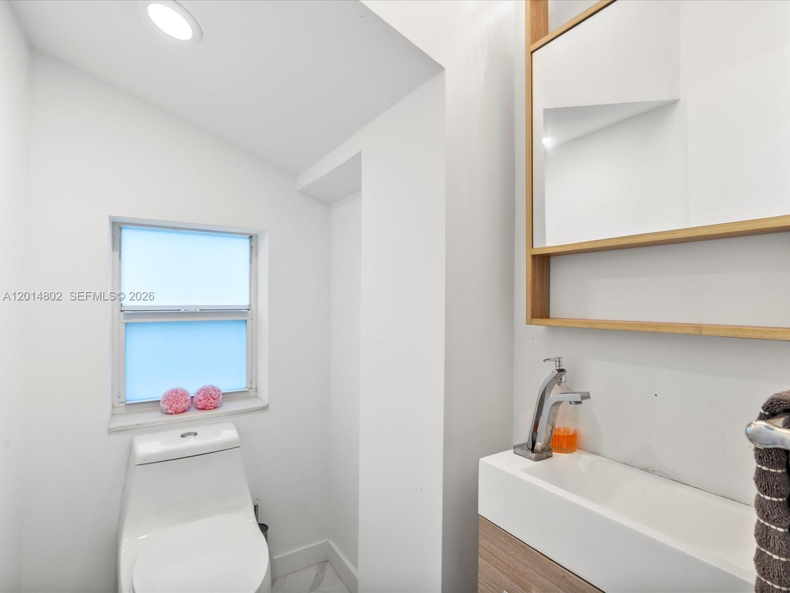 825 Southwest 23rd Road, Unit 1 Miami, FL 33129 - Photo 90 of 92 a bathroom with a sink a toilet and a shower curtain