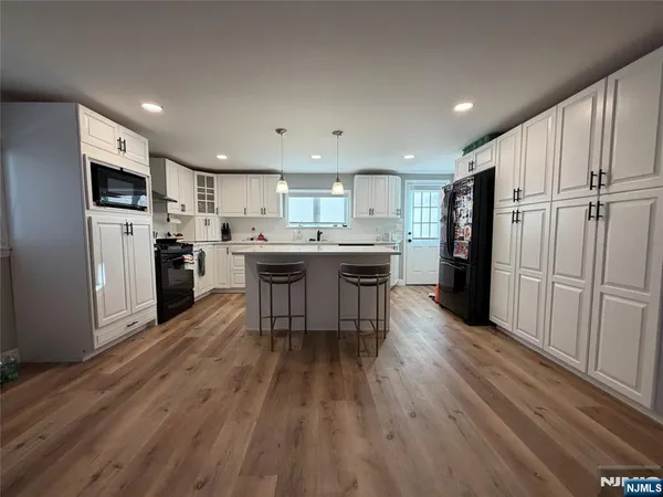 a kitchen with stainless steel appliances granite countertop a refrigerator a stove top oven a sink dishwasher and white cabinets with wooden floor