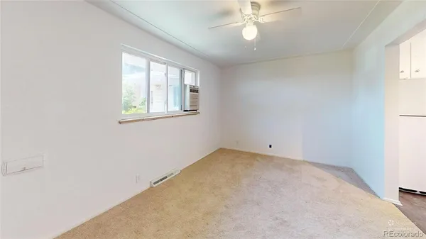 an empty room with windows and fan