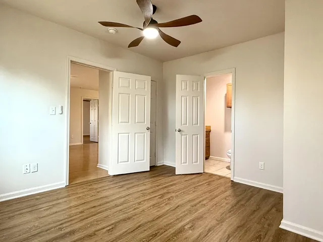a view of empty room with wooden floor and fan