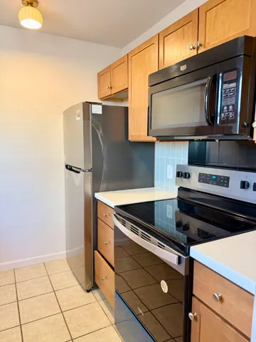 a kitchen with granite countertop a refrigerator and a stove top oven
