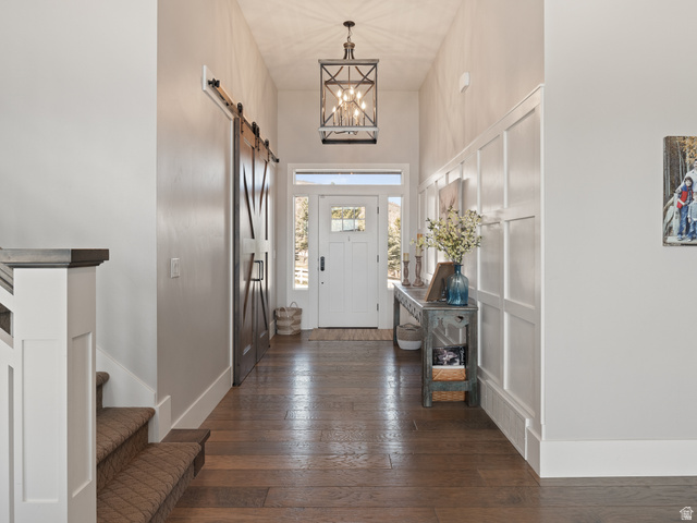 641 West 500 South Midway, UT 84049 - Photo 5 of 52 Foyer featuring wood-finish flooring, a white front door with sidelights, board and batten wall detailing, a dark bronze pendant light fixture, and a dark wood barn door