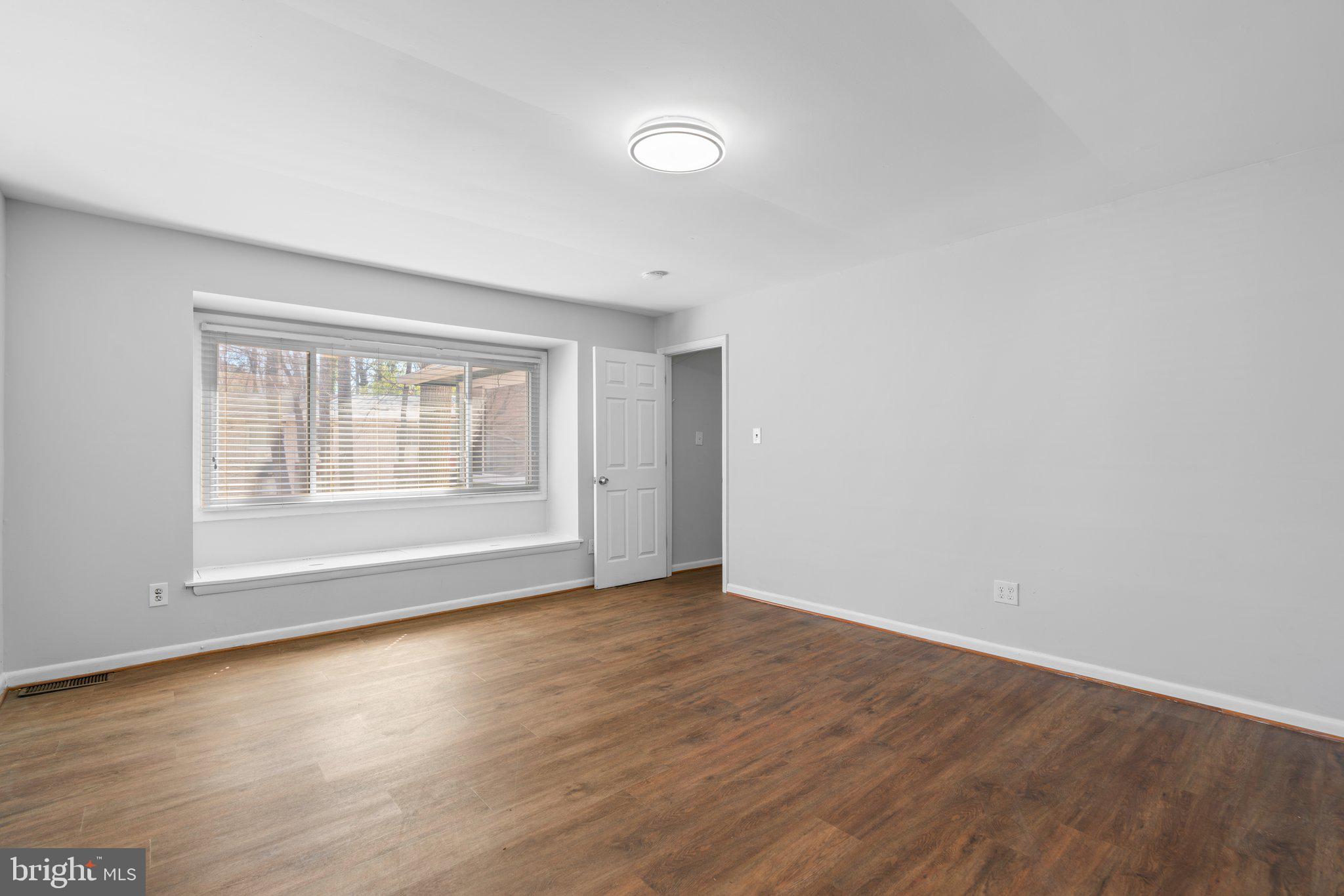 8583 Seasons Way Lanham, MD 20706 - Photo 15 of 25 a view of an empty room with wooden floor and a window