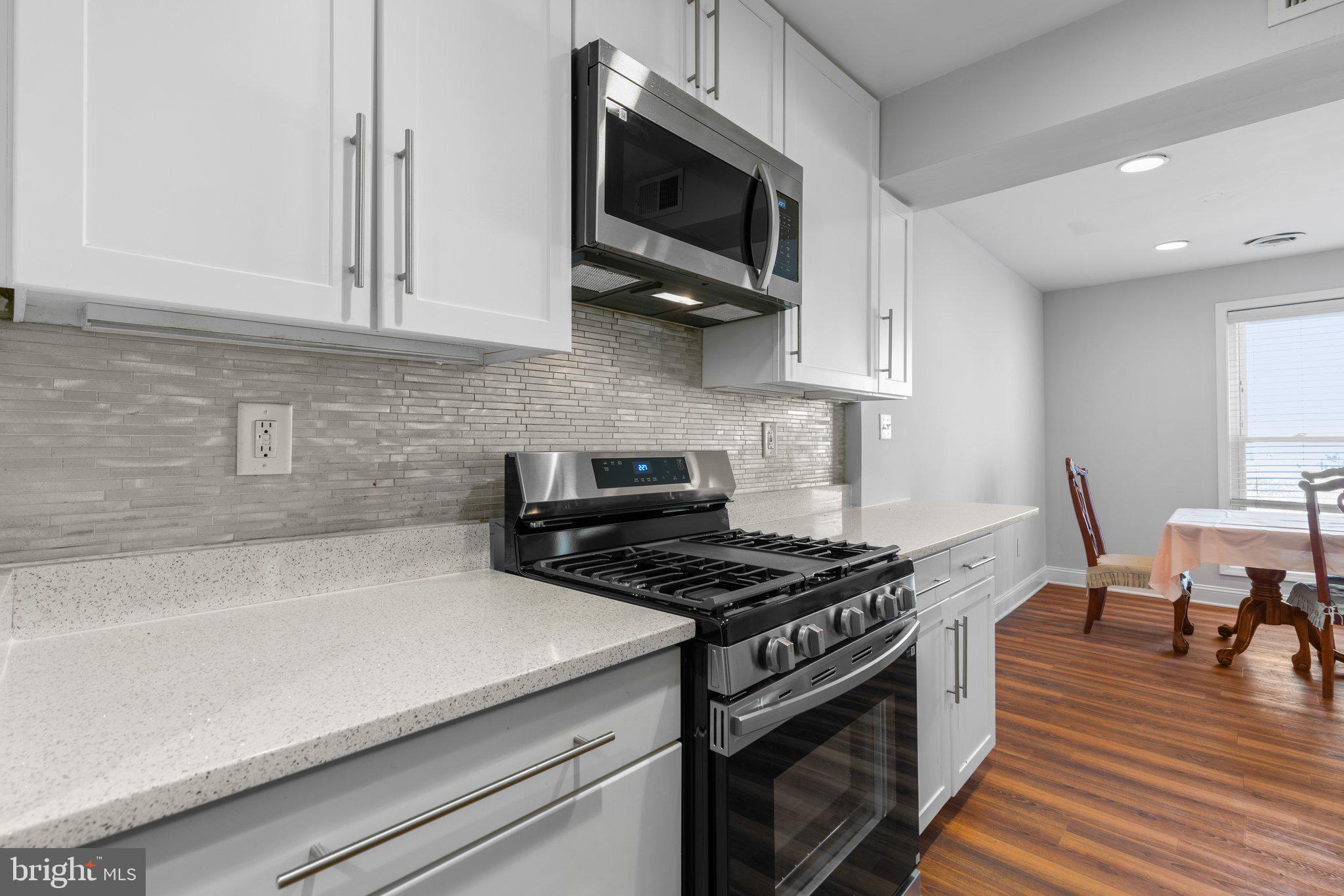 8583 Seasons Way Lanham, MD 20706 - Photo 6 of 25 a kitchen with stainless steel appliances a stove a microwave and white cabinets
