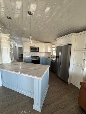 a large kitchen with stainless steel appliances granite countertop a stove a refrigerator a sink and dishwasher with wooden floor